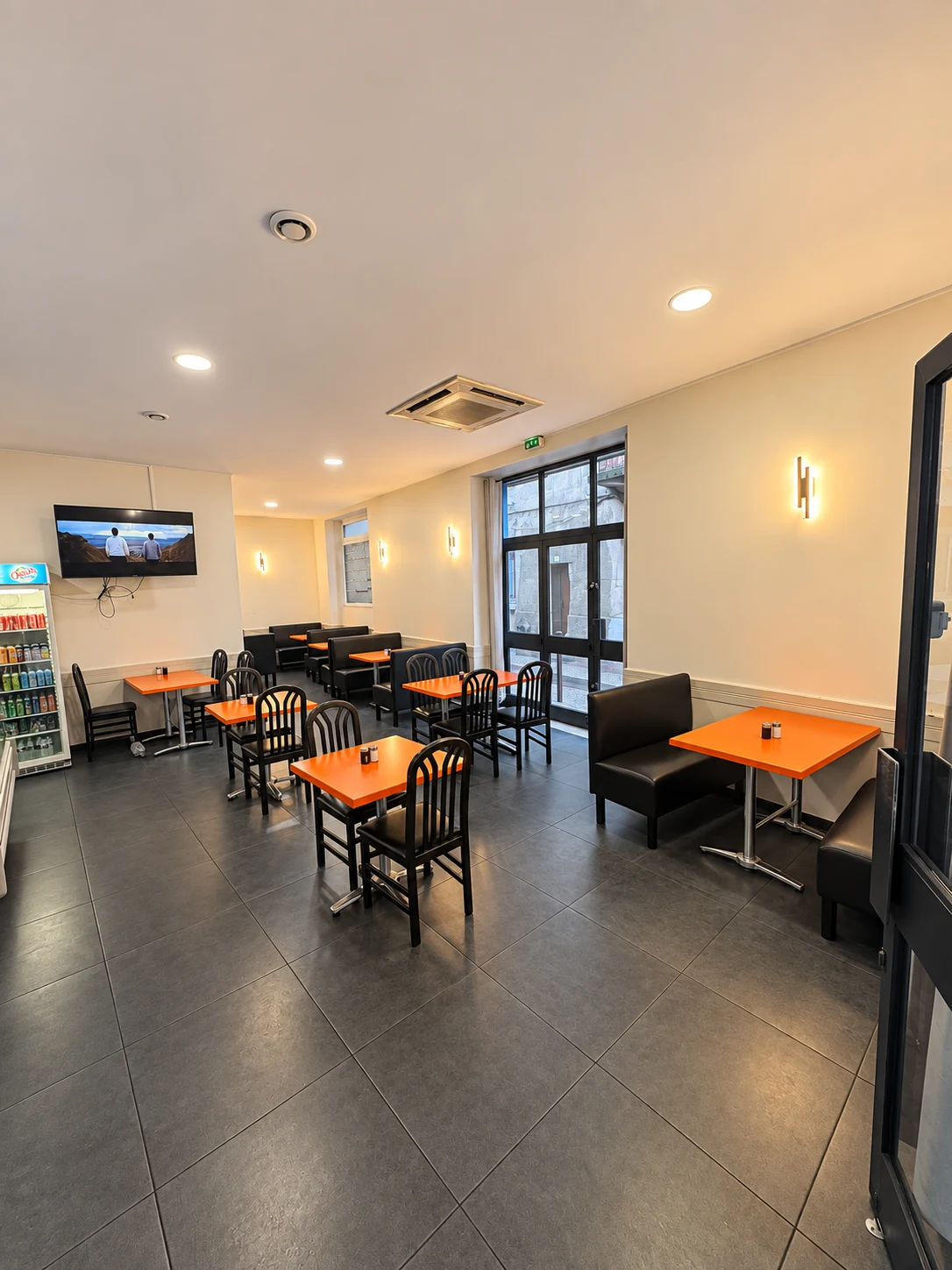 Salle du restaurant avec tables orange et banquettes noires